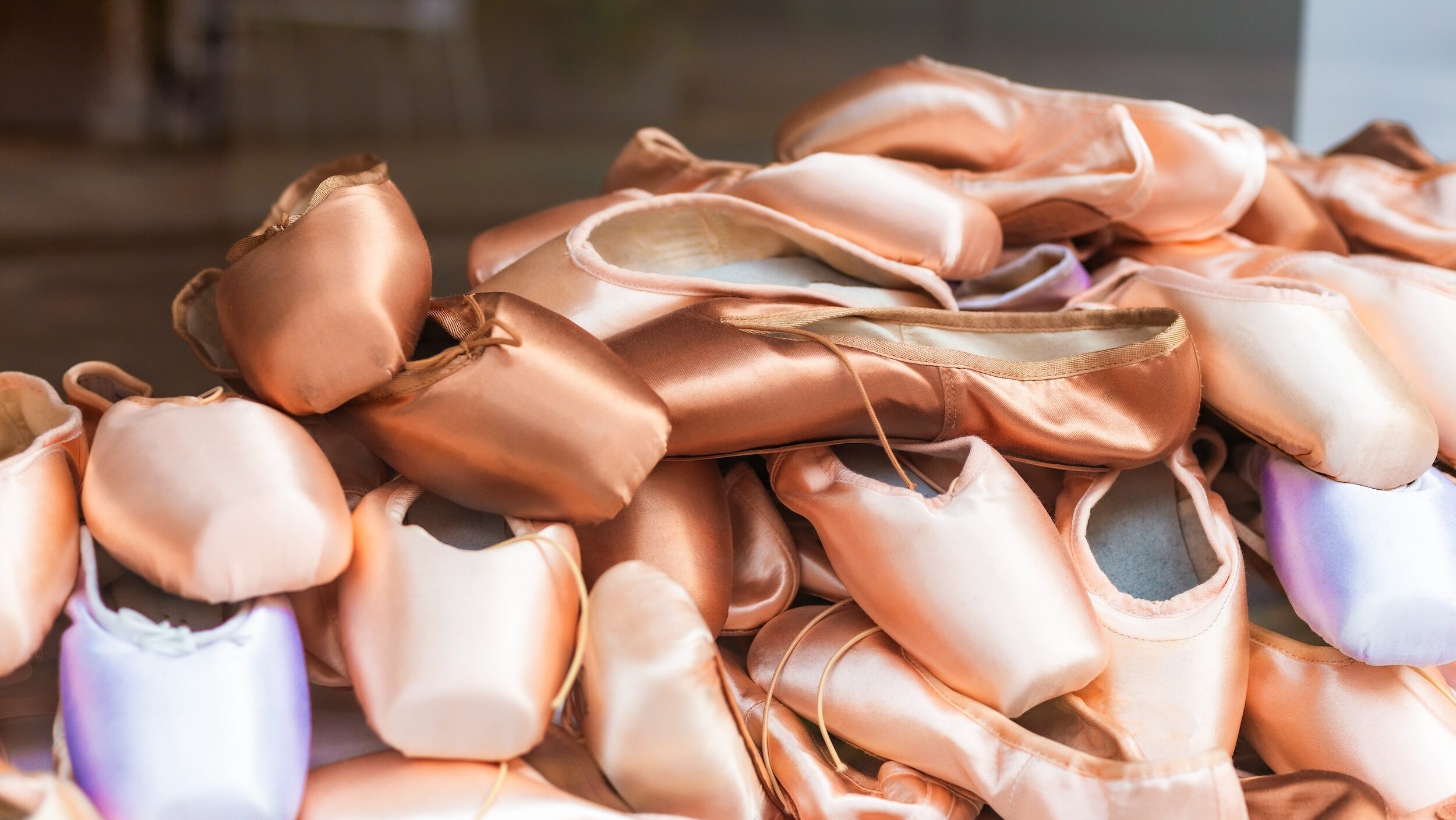 A pile of variously colored pointe shoes.