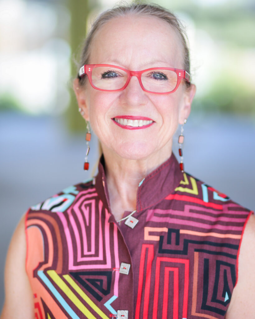 Molly Lynch's headshot. She wears a bright, patterned button-down and pink-rimmed glasses.