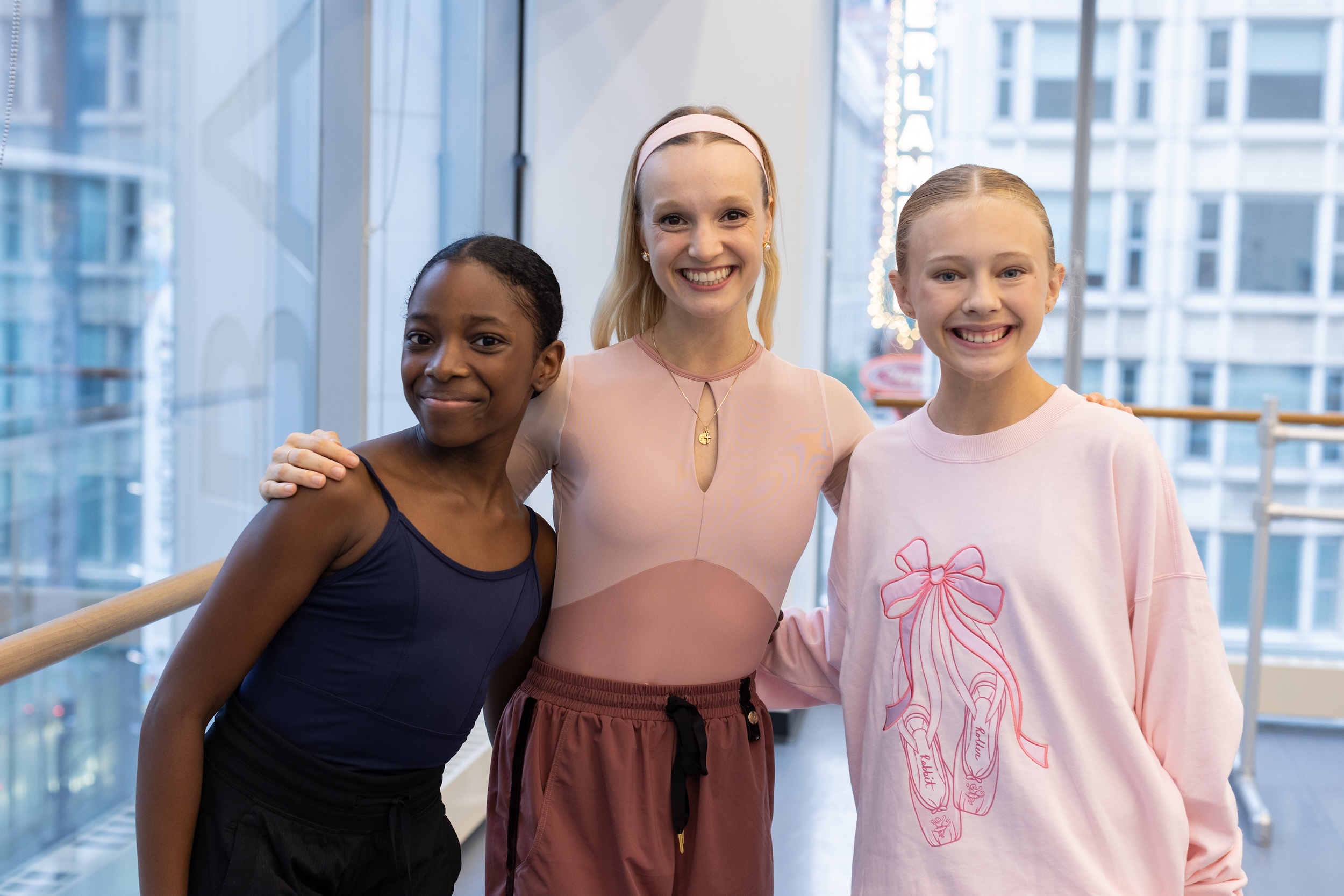 Two ballet students pose with their ballet teacher for a candid photo.