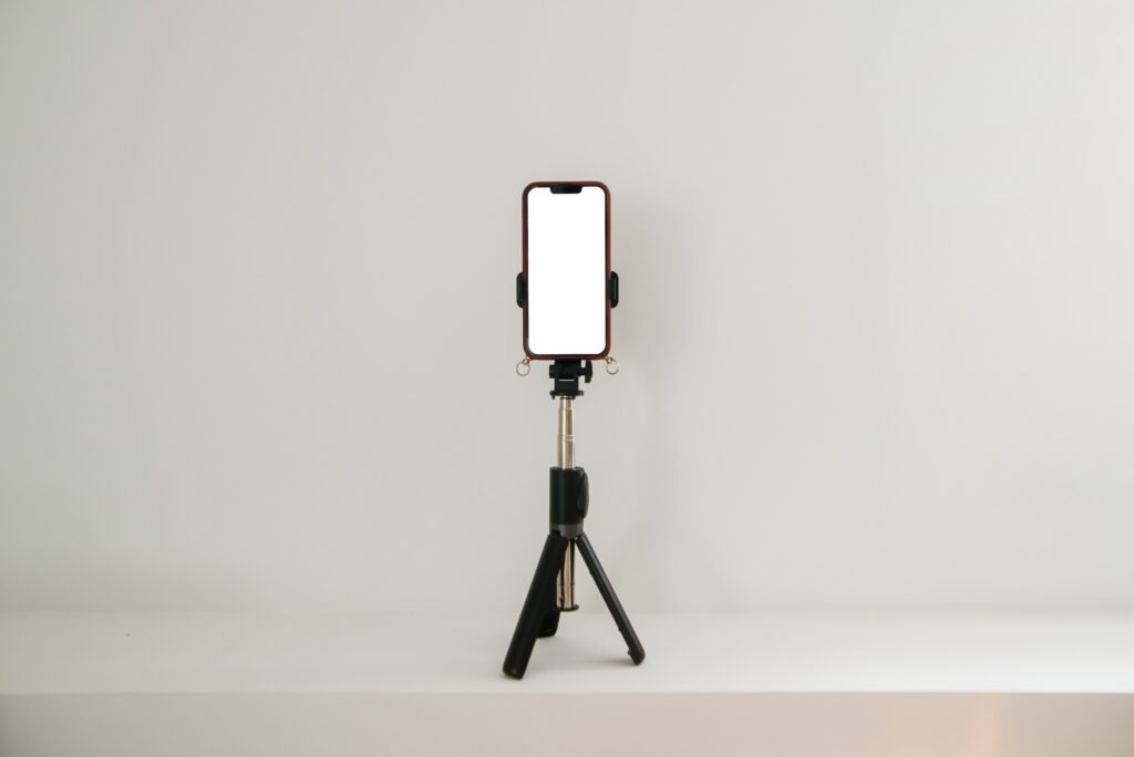 A smart phone with a blank screen rests on a tripod.