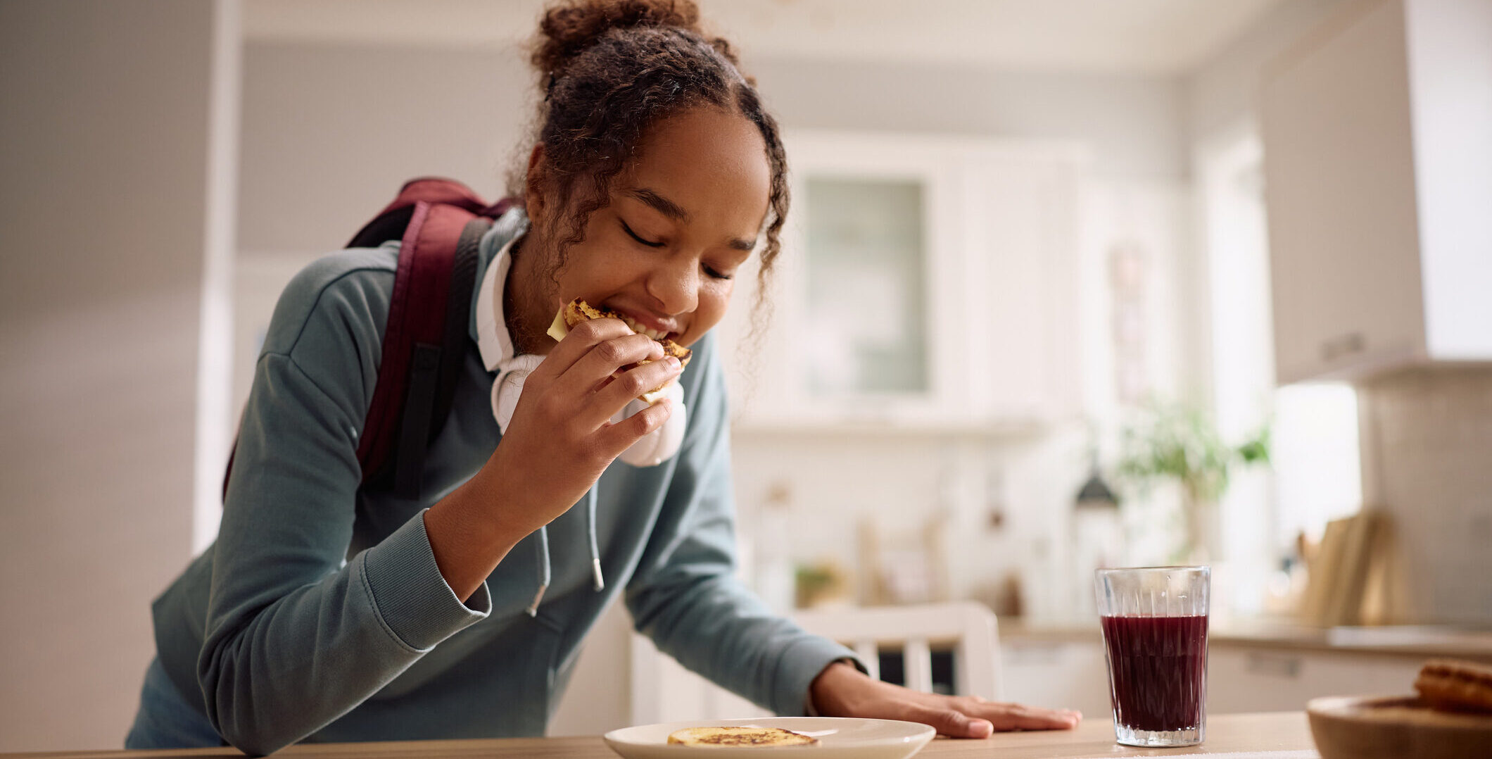 A teenage girl eating breakfast in a hurry before leaving for school.