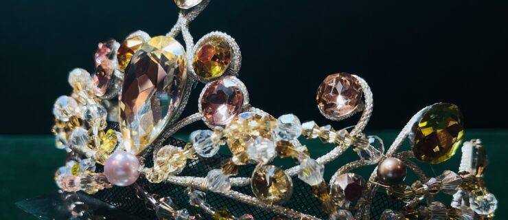 A close-up of a ballet costume tiara with white, amber, and light pink gems.