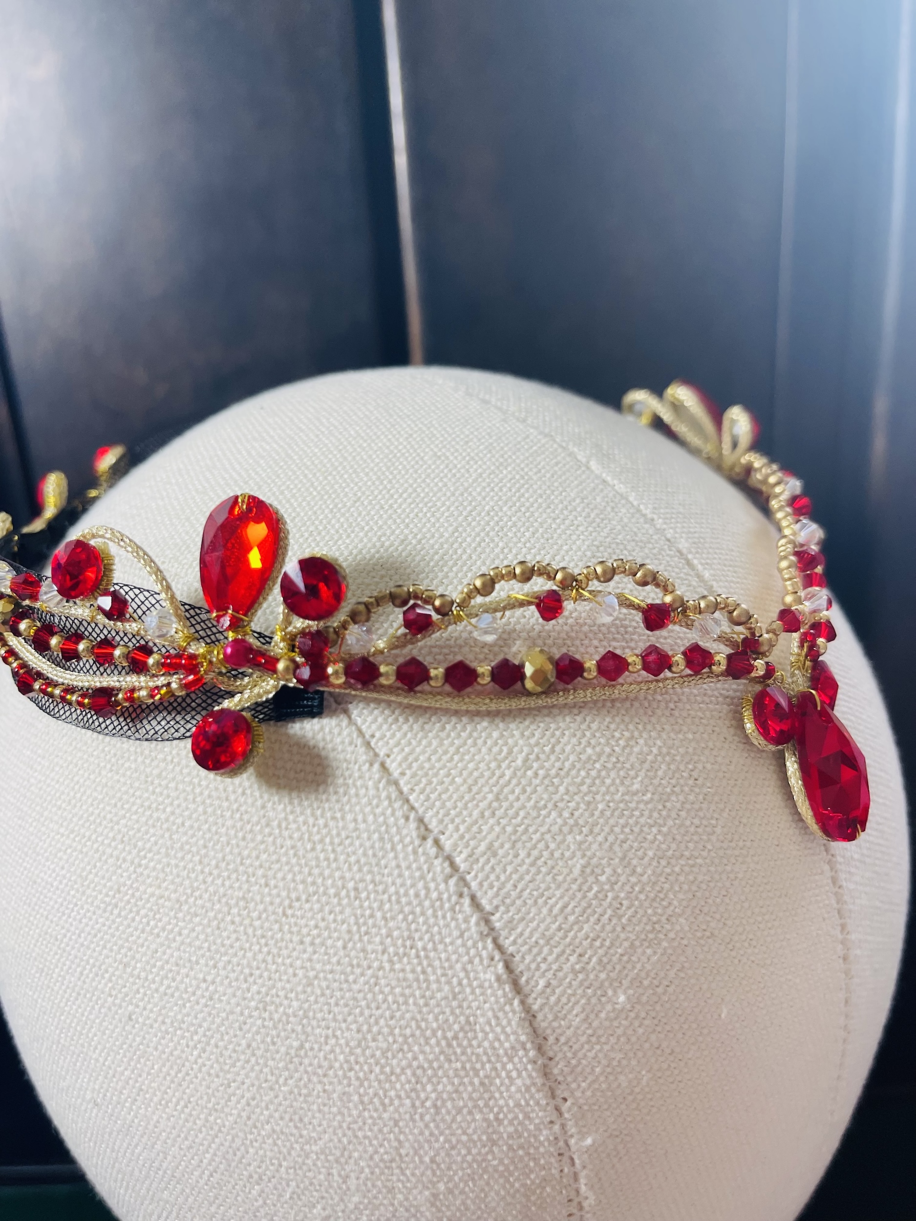 A ballet costume tiara that comes down to a point where the dancer's forehead would be, with red gems of various sizes.
