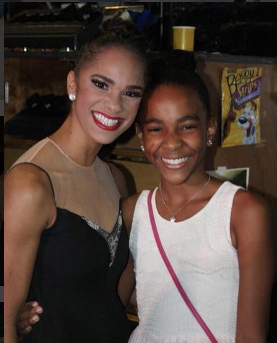 Misty Copeland and a young Nia Faith pose together for a photo wearing formal dresses, smiling widely.
