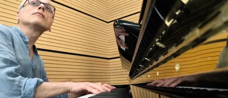 Massimiliano Greco, shown from the chest-up, playing piano during a ballet class.