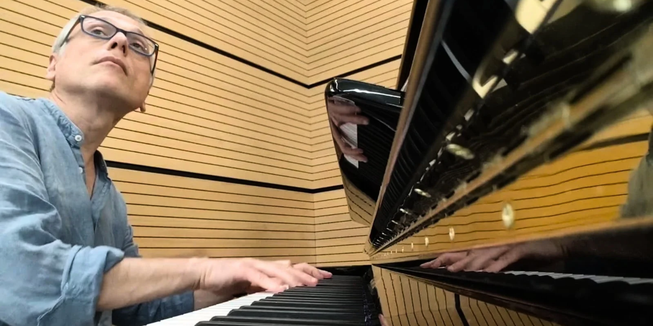 Massimiliano Greco, shown from the chest-up, playing piano during a ballet class.