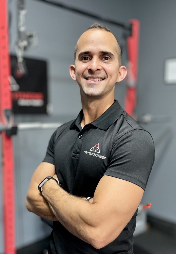 Alex Gonzaga, shown from the waist up, poses with a slight twist and his arms crossed, smiling for the camera. He is in a gym and wears a gray polo shirt.
