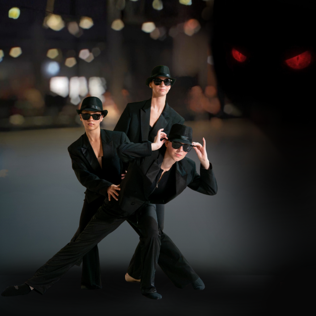 Three dancers from Charleston Ballet are pictured, wearing all-black suits, fedoras, and sunglasses. They pose in a line, one in front of the other, tilted away from each other to look at the camera. In the top right corner of the background, lurks a pitch-black shadow with glowing red eyes.